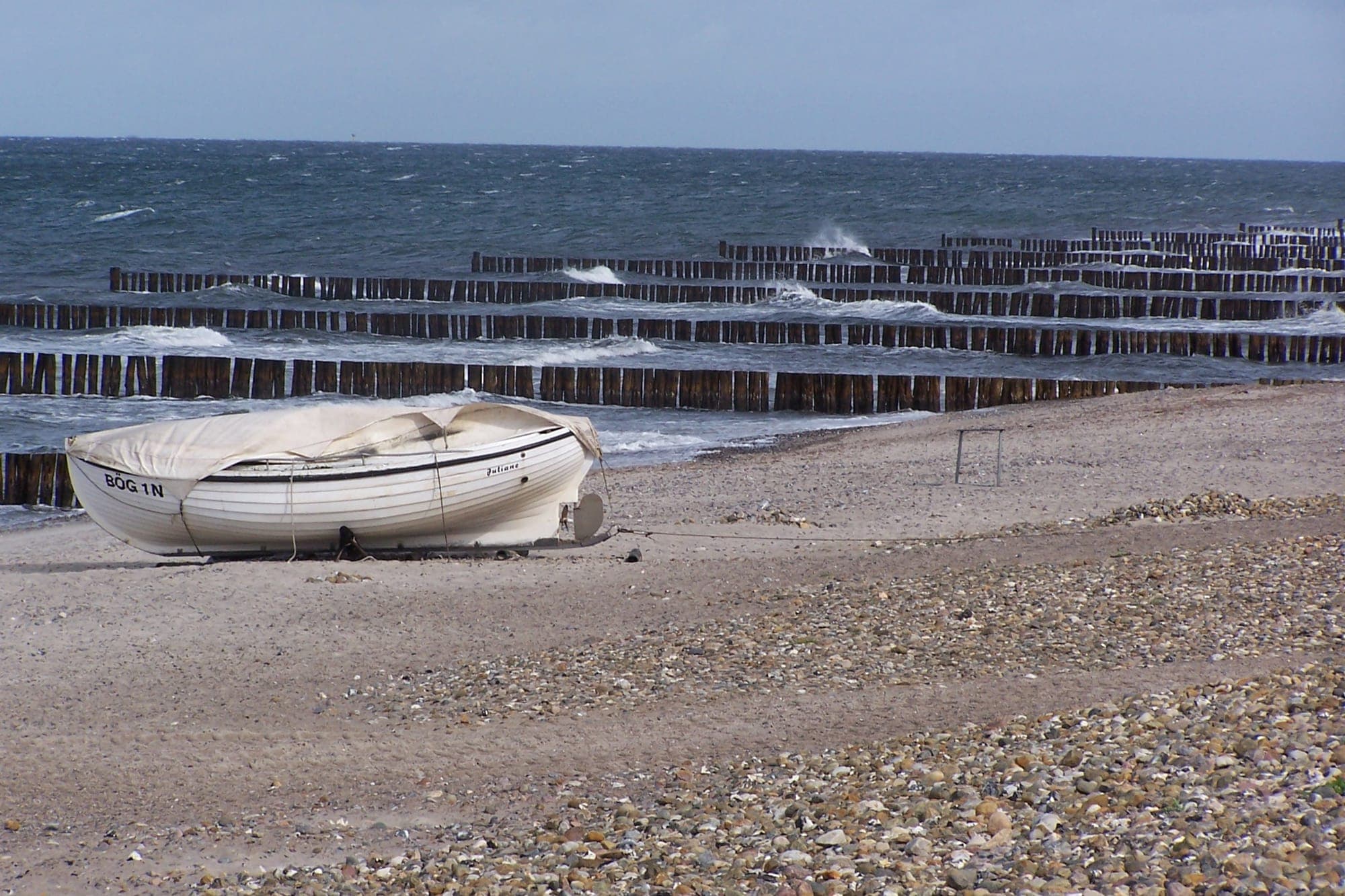 Weißes Boot am Strand von Börgerende vor den Buhnen