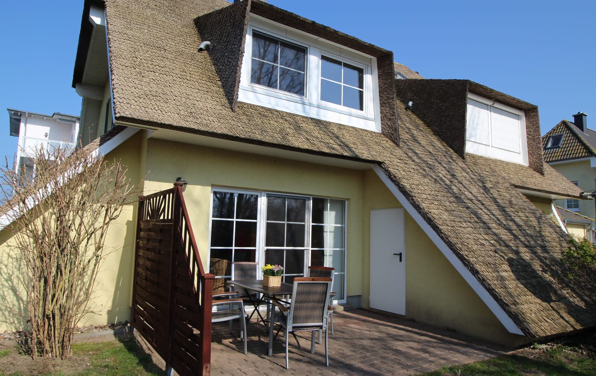 Das reetgedeckte Haus mit Terrasse von der Gartenseite