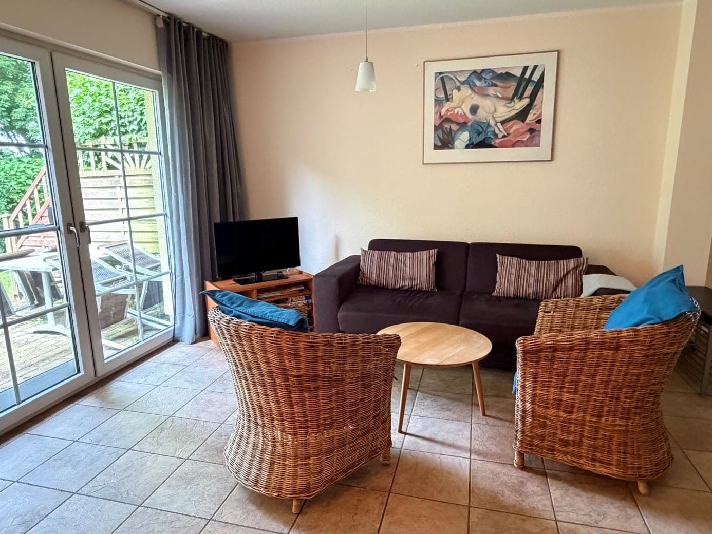 Wohnzimmer der Wohnung I mit Rattansesseln und Terrassentür